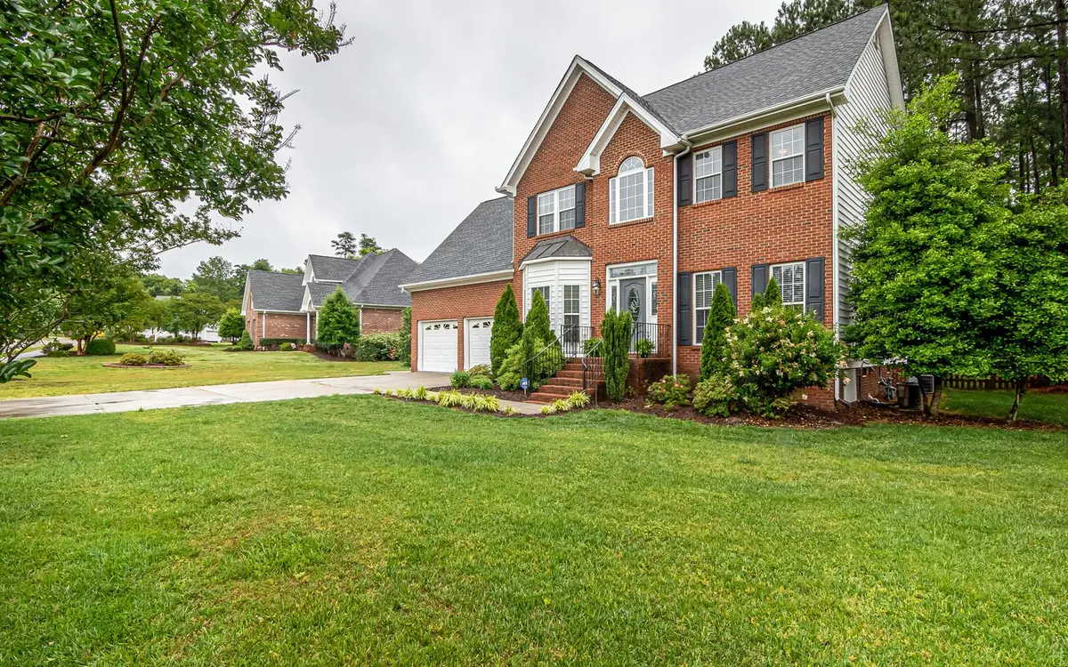 A two-story brick family home with a green lawn