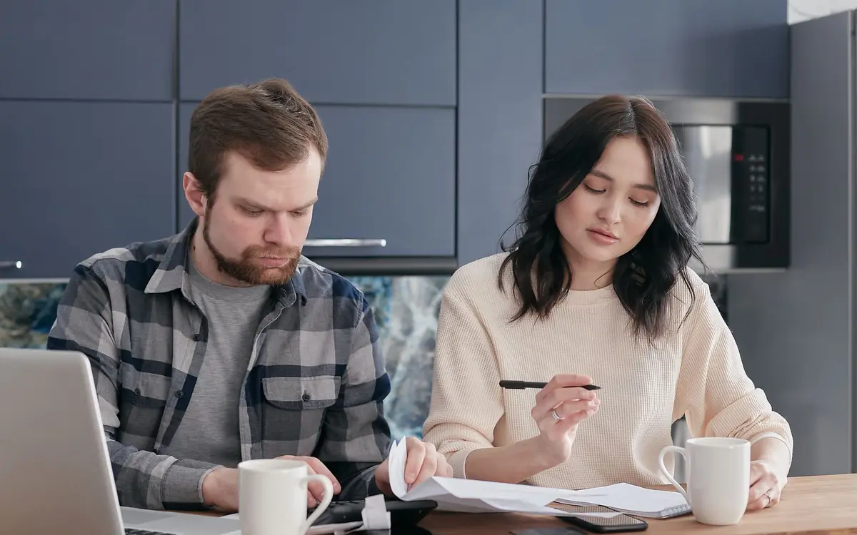 A couple working through documents at a kitchen table